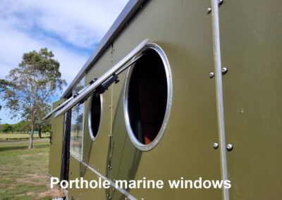 Close-up of a circular porthole marine window on a caravan, highlighting its robust construction and sealing.