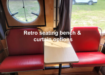 Caravan interior showcasing versatile retro-style bench seating with curtains, ideal for dining or lounging in a compact space.