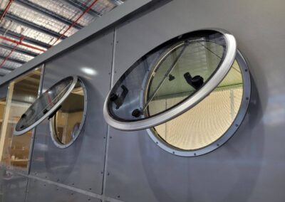 Two opening porthole windows on the side of a caravan, showcasing the design and functionality with screens visible.