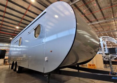 Silver caravan with a distinctive bullnose front design, emphasising aerodynamic shape for superior road handling and stability.