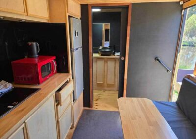 Caravan kitchen space showing a stainless steel sink, microwave, white cabinetry, and a clean, functional design.