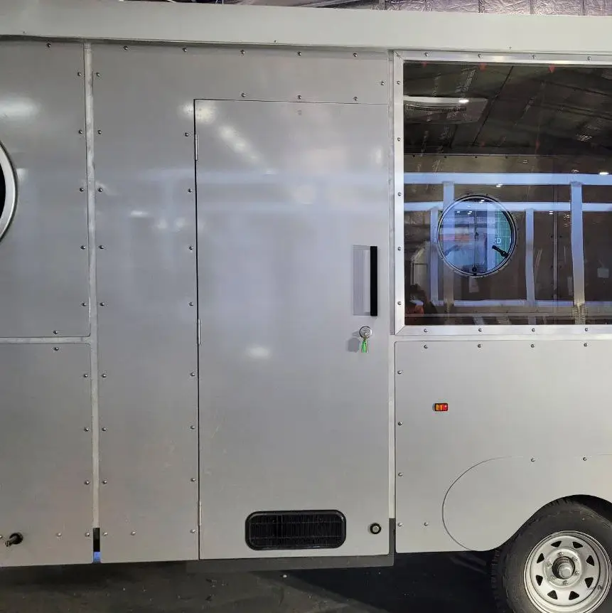 Close-up of an olive green caravan side door with a silver frame, next to a window and a larger clear panel.